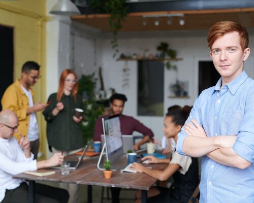 man-standing-beside-people-sitting-beside-table-with-laptops-3184395