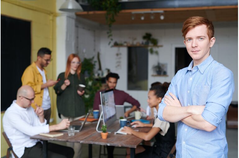man-standing-beside-people-sitting-beside-table-with-laptops-3184395